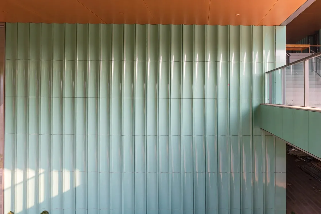 Ground-floor facade wall of the Haitang Living Room, showing the consistent texture and sky-green luster of LOPO glazed terracotta panels at a human scale.