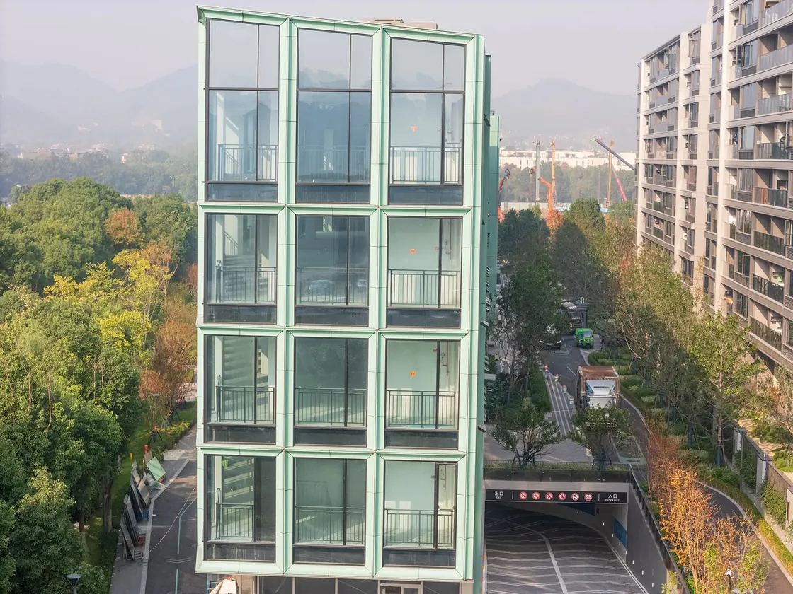 The lateral elevation of Haitang Living Room and its surrounding streetscape, showcasing how LOPO’s terracotta facade integrates into the urban fabric of Liangzhu New Town.