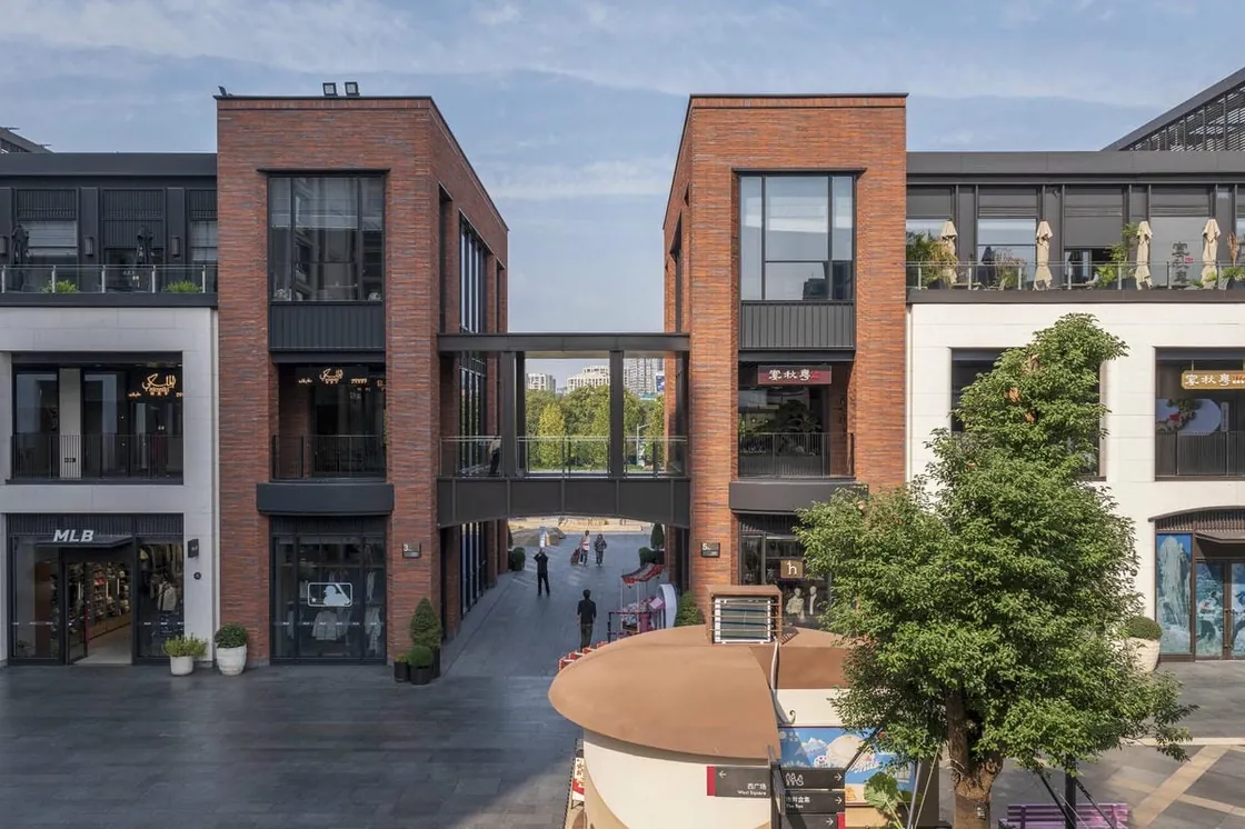 Red clay facing brick retail volumes connected by a bridge at Yiwu Place