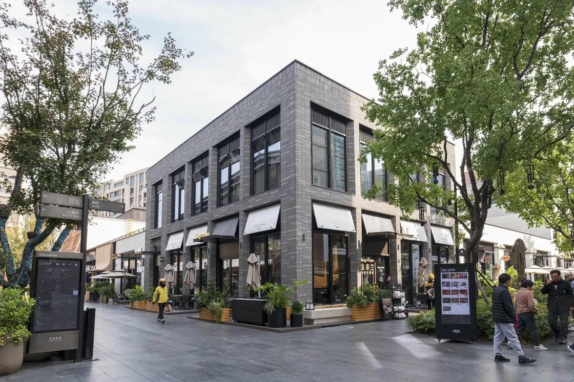 Gray clay facing brick building at a landscaped street corner in Yiwu Place