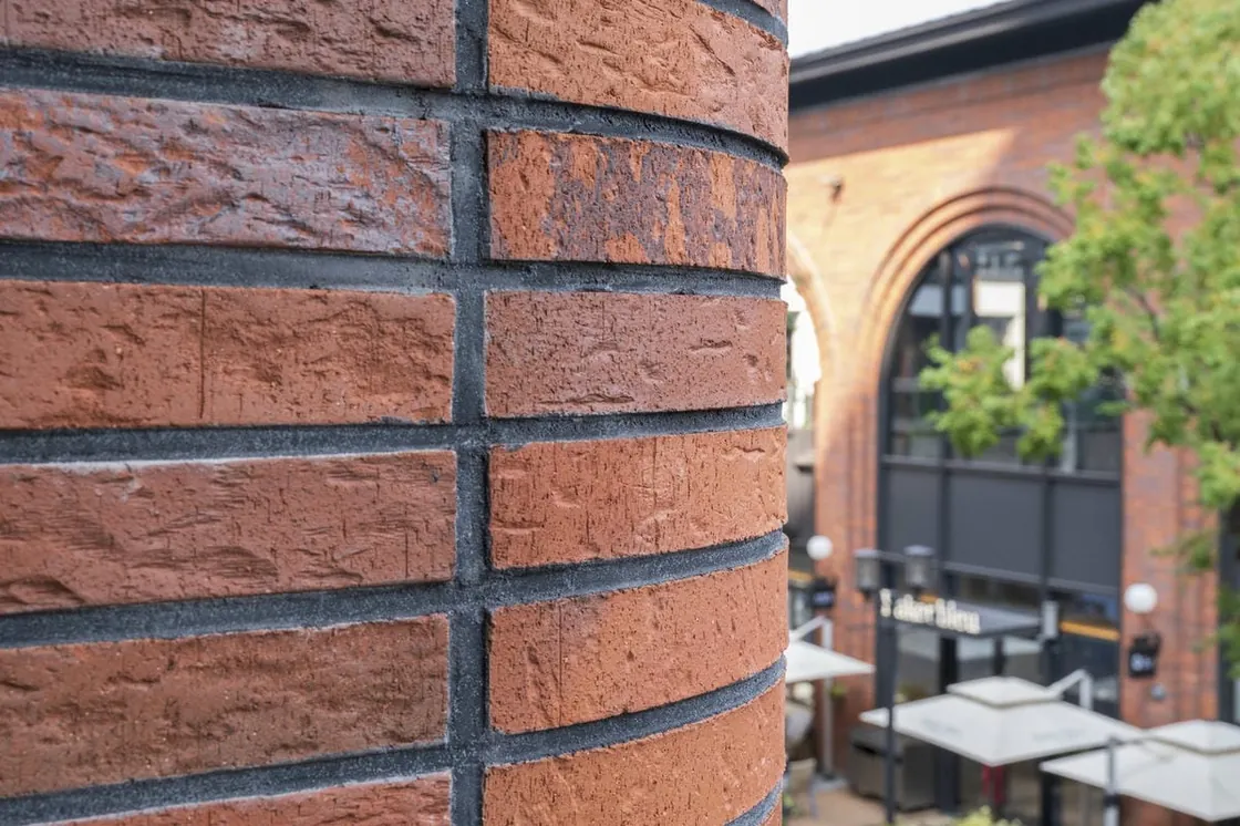 R250 curved red clay facing brick forming a rounded facade corner at Yiwu Place