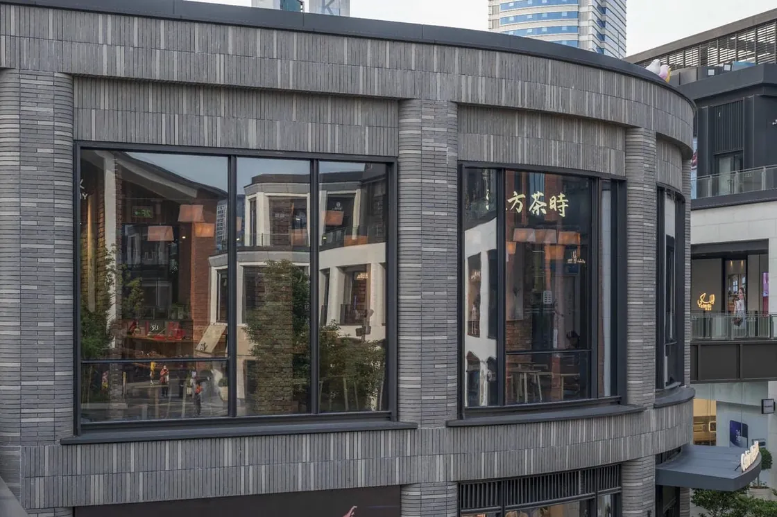 Closer view of gray clay facing bricks wrapping a curved facade at Yiwu Place