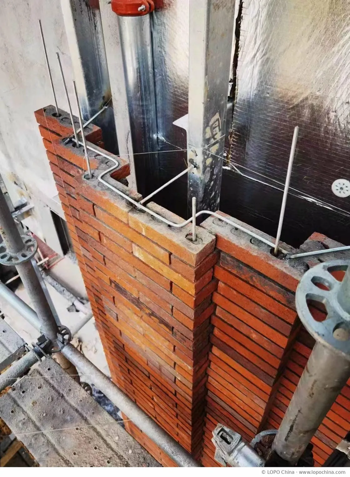 Steel bars threaded through clay facing bricks during facade installation at Yiwu Place