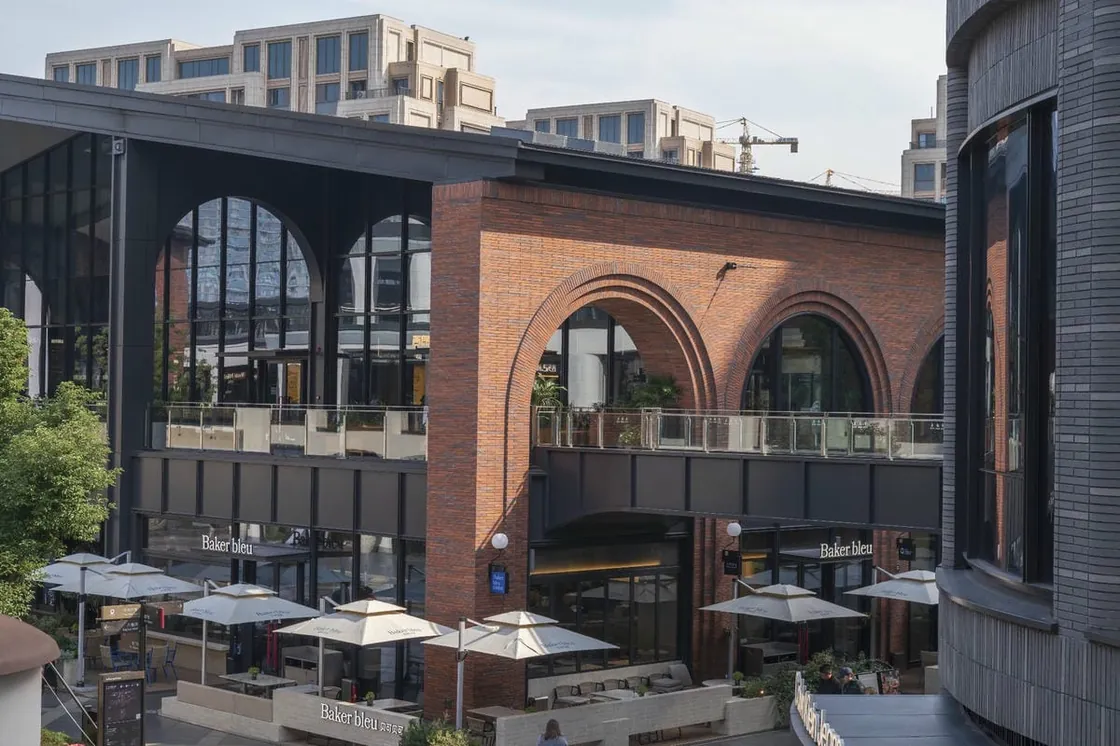 Red brick arched facade overlooking an outdoor terrace at Yiwu Place
