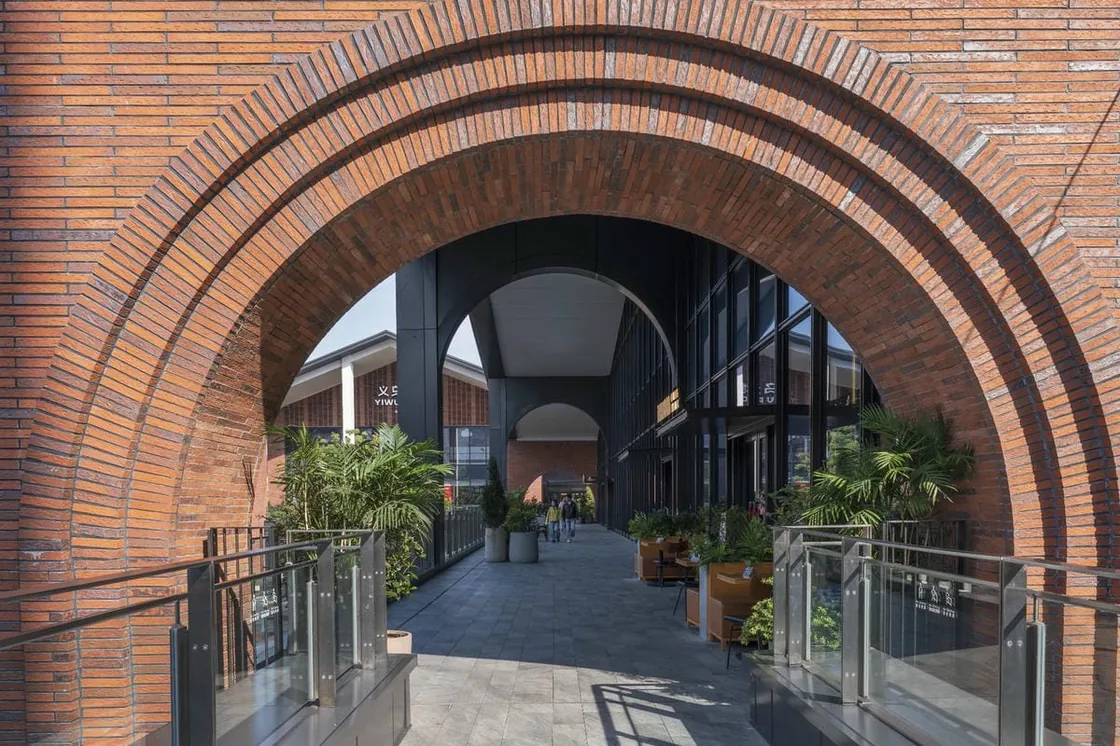 Red brick arch framing a pedestrian passage at Yiwu Place