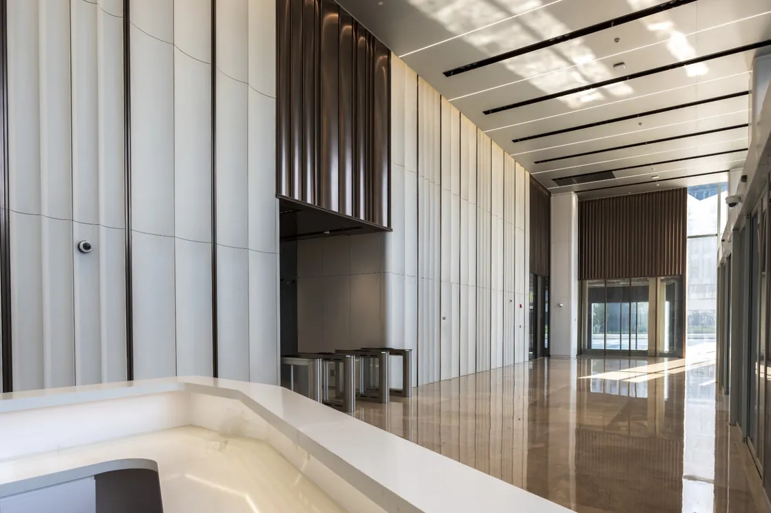 Sunlit Bofeng Center lobby with white concave-profile terracotta walls and dark architectural elements.