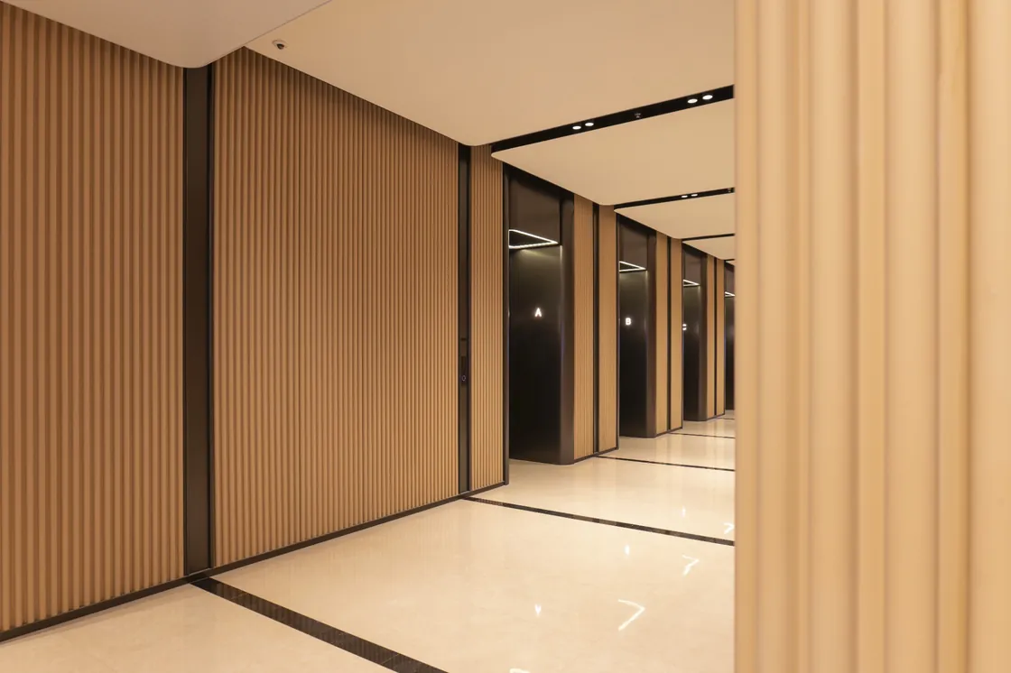 Yellow ribbed terracotta cladding beside dark lift entrances in EIC's public interior.
