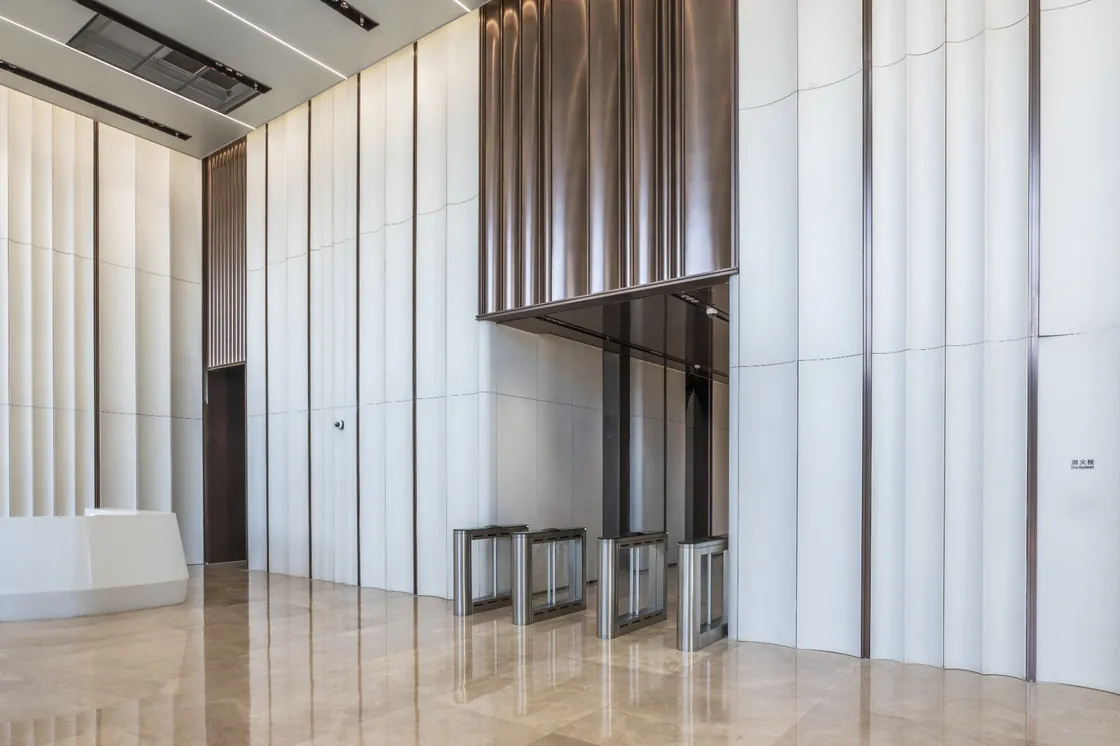 Bofeng Center lobby with white profiled terracotta walls, a dark entrance canopy and access gates.