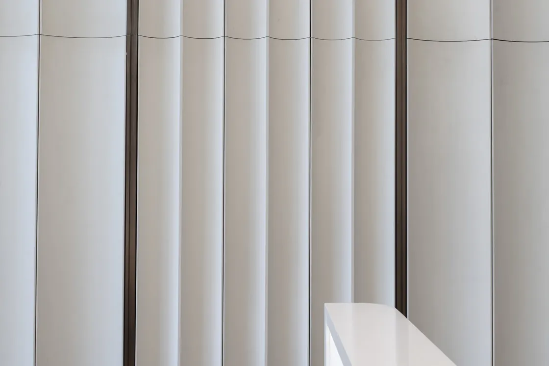 Close-up of inward-curving white glazed terracotta faces separated by vertical joints at Bofeng Center.