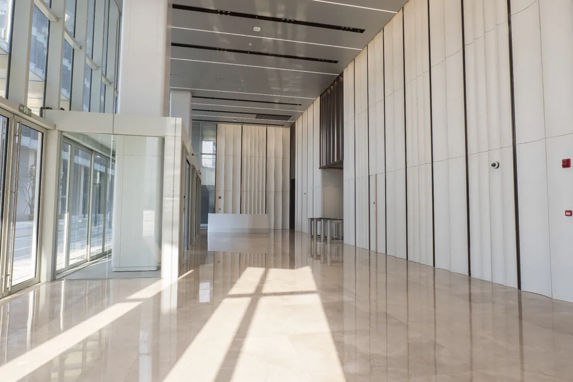 Daylit Bofeng Center lobby with tall white terracotta walls, glazing and reflections on the floor.